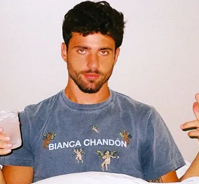 Actor Justin Assada wearing a gray T-shirt and holding a glass in his hand