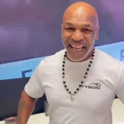 Mike Tyson is smiling wearing a white shirt.