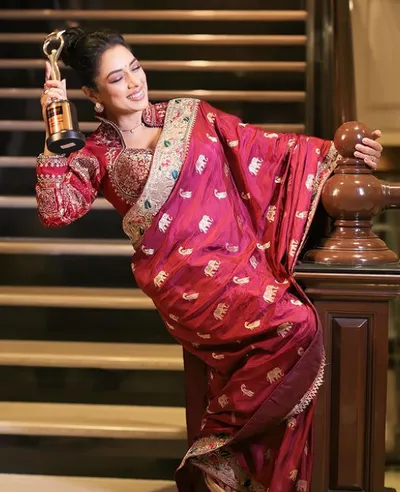 Rupali Ganguly An Indian woman in red saree posing beautifully on a staircase.